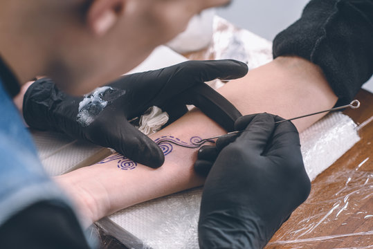 Male artist in gloves working on arm piece tattoo in studio