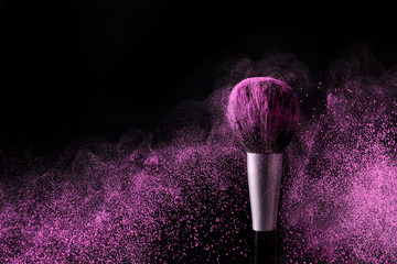 Brush for makeup with purple make-up shadows in motion on a black background. - obrazy, fototapety, plakaty