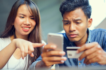 close up asian man using smartphone for payment by credit card and woman trying to help concept