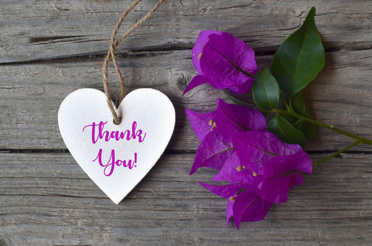 Thank You or thanks greeting card with bougainvillea flowers and decorative white heart on wooden background.Selective focus.