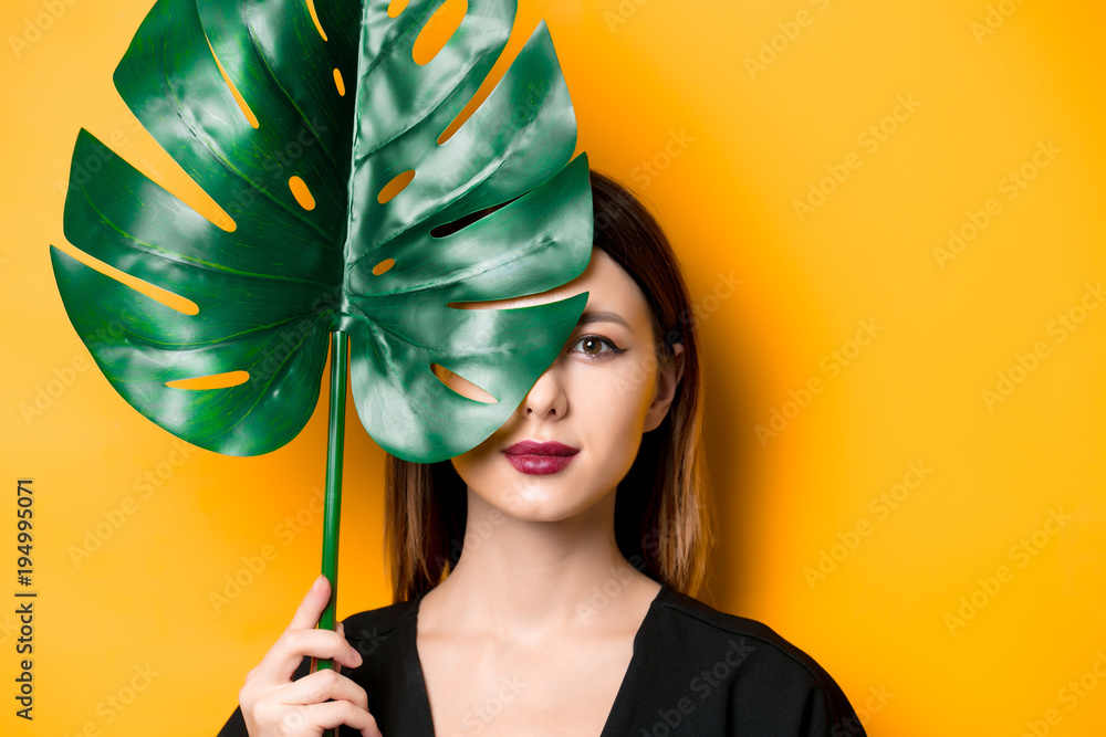 Poster beautiful woman in dark clothes with palm leaf