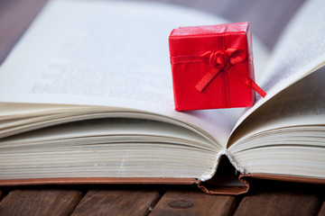 Red gift and book on wooden table