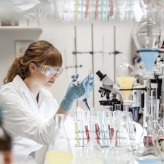 Life scientists researching in laboratory. Focused female science professional pipetting solution...