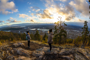 Obraz premium Two girls are admiring the cloudy sunset over the city in the valley
