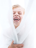 Close up of cheerful boy in curtains
