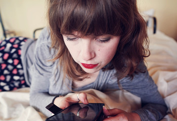 Mujer joven atendiendo su teléfono móvil desde la cama 