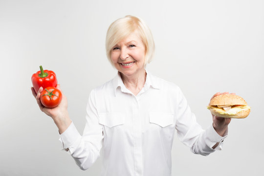 A picture of dilemma that this lady has. There is a good and healthy meal on one side and tasty but not healthy hamburger on the other side. Isolated on white background