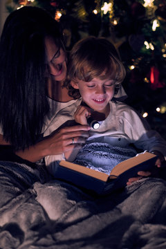 Boy reading book with flashlight