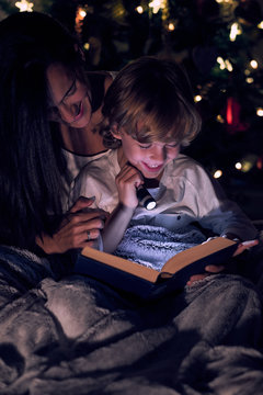 Boy reading book with flashlight
