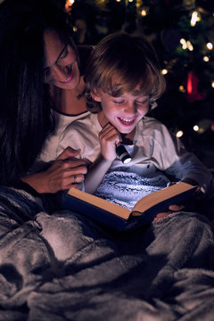 Boy reading book with flashlight