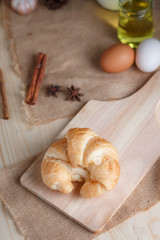 Croissant on wooden cut board on table wood and fabric select focus shallow depth of field