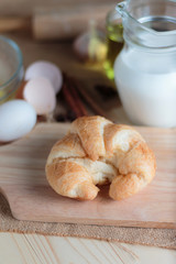 Croissant on wooden cut board on table wood and fabric select focus shallow depth of field