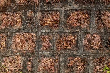 Vintage red brick wall with rough surface and dark stain taken from an old town in India Goa. The pattern and brickwork texture give it an industrial background look.