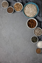 Ingredients for cooking homemade granola: oatmeal, raisins, coconut chips, honey, peanuts, cocoa, blueberries, vegetable oil, flax, sesame, pumpkin and sunflower seeds. Concrete background. Top view.