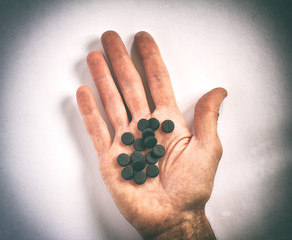 dirty human palm with many of black pills