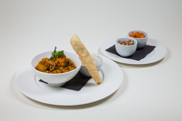 Indian Curry in a white bowl with rice on a white plate on a white background isolated