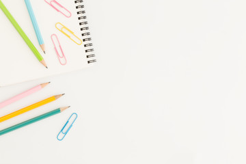 Flat lay photo of office desk with colorful pencil and paper clip,copy space top view