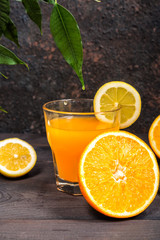 Orange juice in a glass beaker and citrus slices on a dark background with copy space