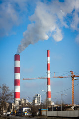 Fototapeta na wymiar The power station with two smoke stacks and crane