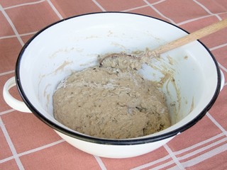 Homemade bread dough/
Traditional dough preparation for homemade bread. Hand mixing with a wooden spoon in the enameled metal bowl. Slant top view.