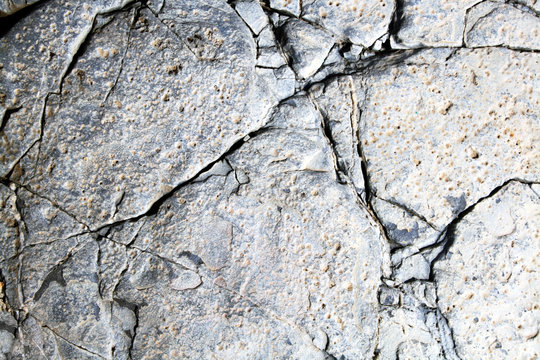 Rock wall. Close-up of a gray rock wall with a very well-structured stone structure. The stone has large and small cracks in various widths.