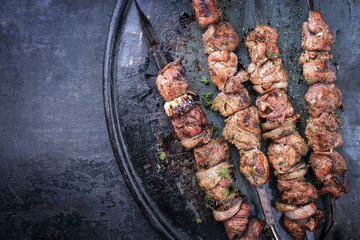 Traditional Russian shashlik on a barbecue skewer with roasted onion as top view on old board with...