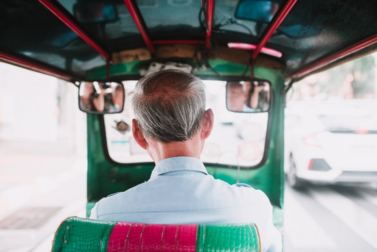 Senior man driving auto rickshaw on city street