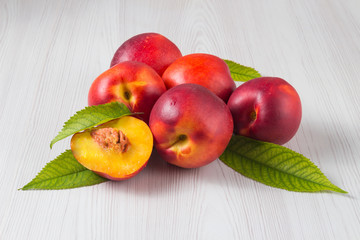 Peaches with leaves on a white wooden table