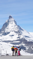 Group of travelers taking picture with the view of Matterhorn peak in the background, Zermatt, Switzerland, May 2017