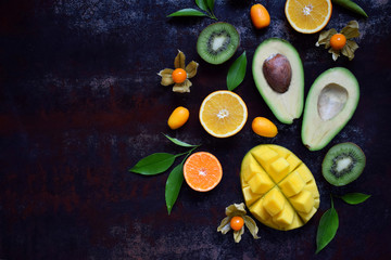 Fototapeta na wymiar Mix of ripe tropical fruits with avocado mango, kumquat, kiwi, citrus. Superfood background. Vegetarian raw food. Copy space