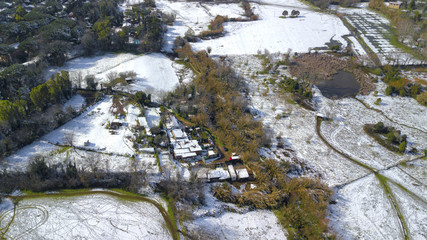 Aerial view of the aqueduct park in Rome, Italy. The park is covered by snow and ice on a cold winter day. Some small houses can be seen on the lawn.