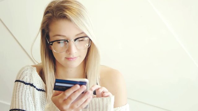 Young woman using mobile cell phone shopping online with credit card in cafe 