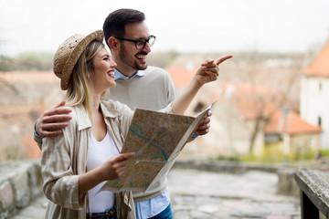 Happy tourist couple with map traveling outdoors
