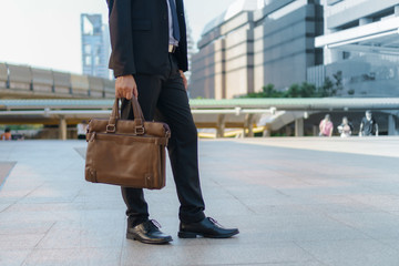 Businessman walking in the city and holding briefcase