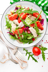 Chicken fillet salad with tomato, lettuce, cucumber and arugula leaves. Fresh vegetable salad with chicken meat. Healthy food. White wooden background. Top view