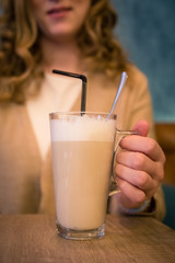Female hand who hold cup of latte coffee. Close up