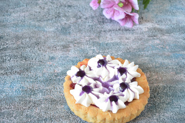 Dessert with jam and cream. Dessert with cream in a basket. Cake in lilac tones. Dessert on the background of flowers.