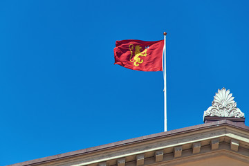 Royal Standard of Norway featuring a golden lion over a red field waving on blue sky background