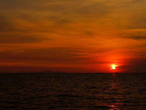 sunset last on horizontal in right frame over orange sky and ocean