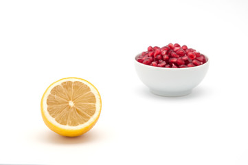 Lemon in the foreground and a cup of pomegranate seeds in the background.
