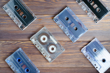 A lot of old audio cassettes. Wooden background. Space for text