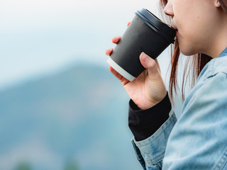 coffee break and relax concept from beauty asian woman with long hair hold black plastic coffee cup drink and relax with layer of mountain background