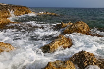 Fototapeta na wymiar coastal stones at sea foam from the waves