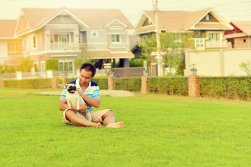 Happy Asian man playing with his dog in garden
