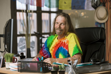 Fototapeta na wymiar Smiling Man with Long Hair in a Colorful Office