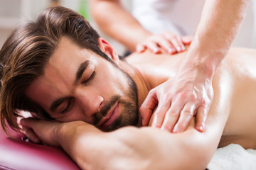 Young man is enjoying massage on spa treatment. 
