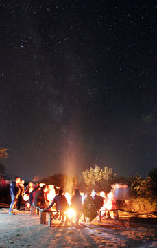 The people rest near a bonfire on the starry sky background. evening night time. long exposure