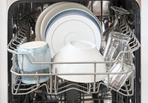 dishes in the basket of a dishwasher, ready for cleaning, selected focus, very narrow depth of field
