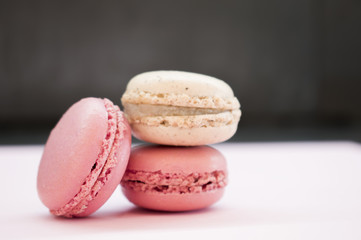 Tender pink and cream macarons on black stone background. soft focus