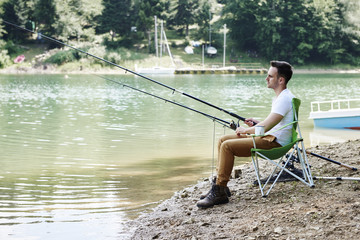 Men with fishing rod sitting on fishing chair